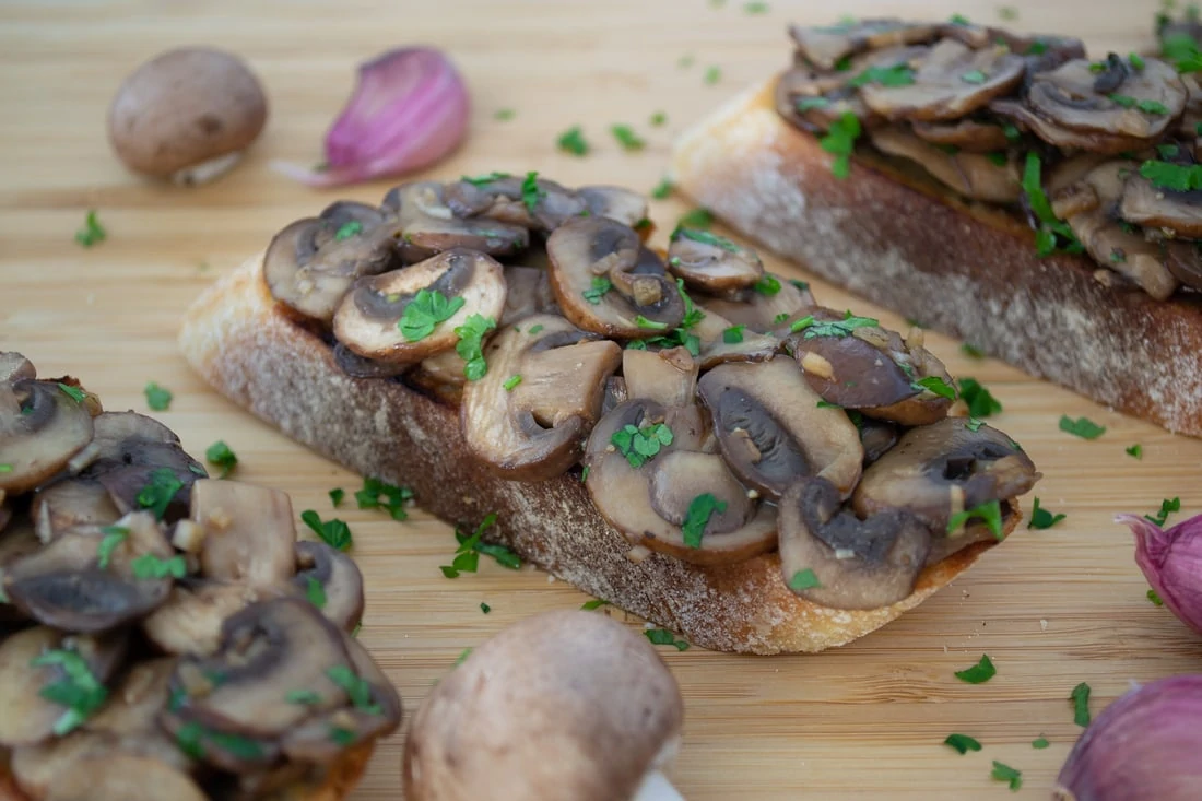 Champignon Bruschetta - drei Ciabatta-Scheiben, belegt mit gebratenen Champignons und garniert mit gehackter Petersilie