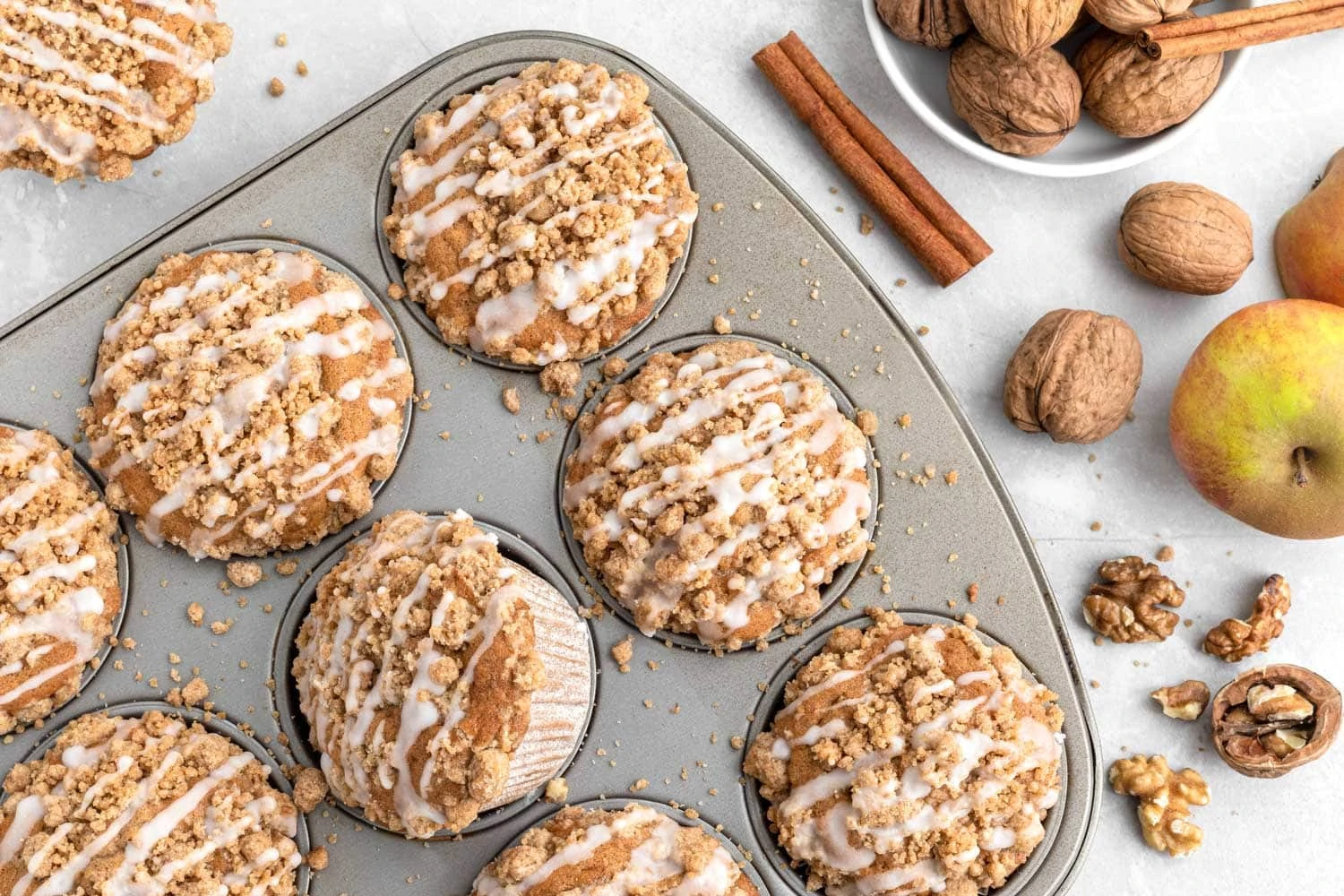 Saftige Apfel-Walnuss-Muffins mit Zimtstreuseln in einem Muffinblech von oben.