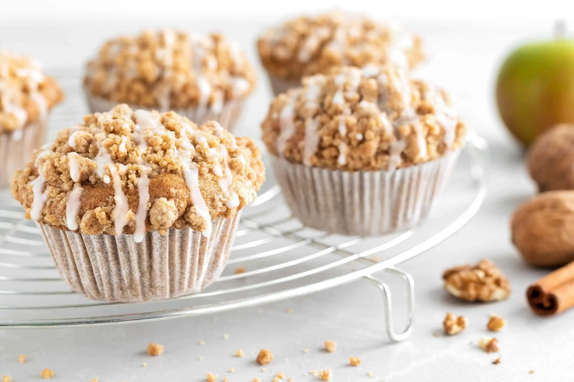 Saftige Apfel-Walnuss-Muffins mit Zimtstreuseln auf einem runden Abkühlgitter.