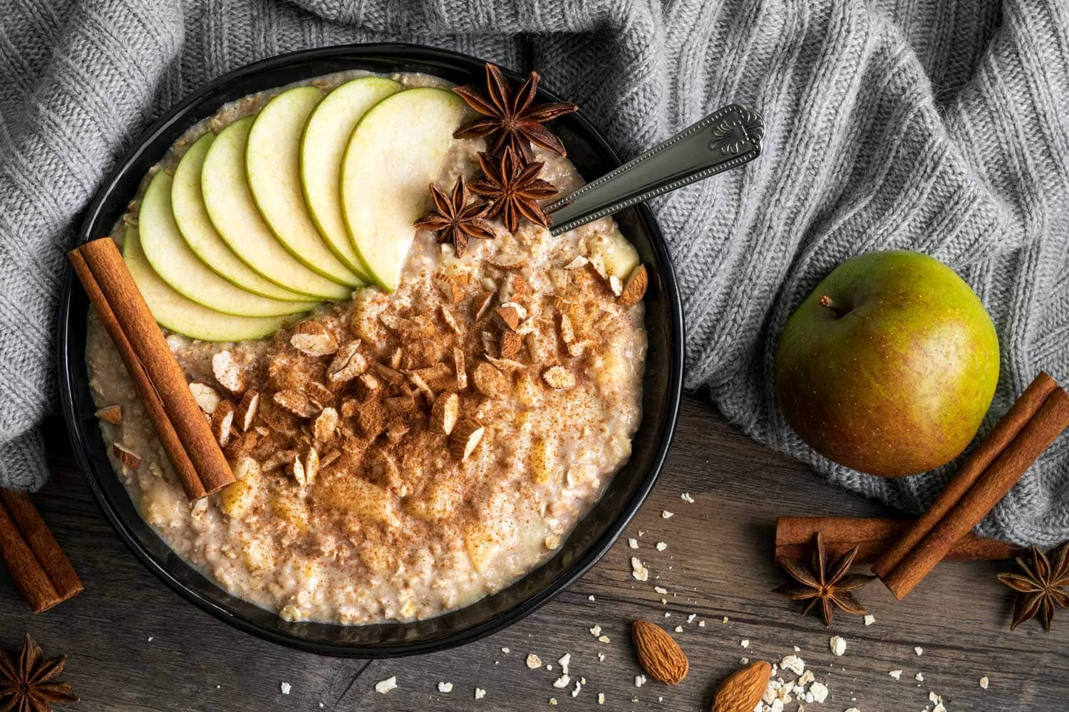 Porridge mit Apfel und Zimt in einer Schüssel mit Löffel, garniert mit verschiedenen Toppings.