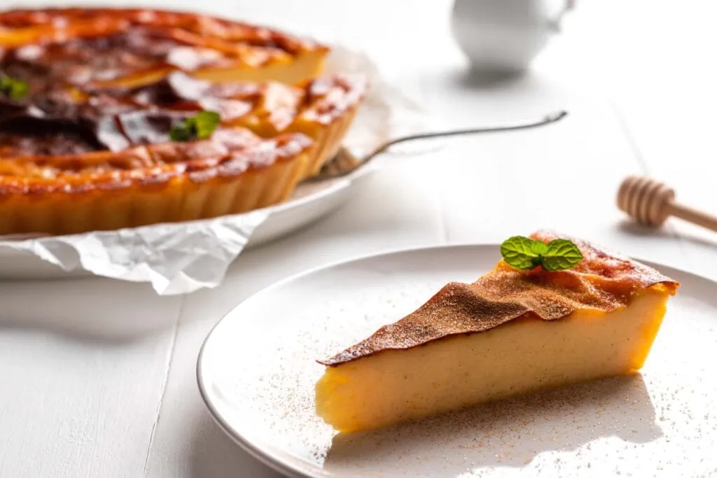 Griechischer Kuchen mit Grieß, Galatopita, auf einem Kuchenteller garniert mit frischer Minze, Zimt und Zucker.