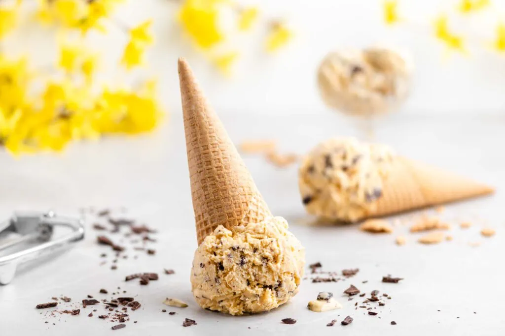 Eierlikör-Eis in zwei Waffeln und einem Eisbecher. Neben dem Eis liegen Schokoladenstücke.