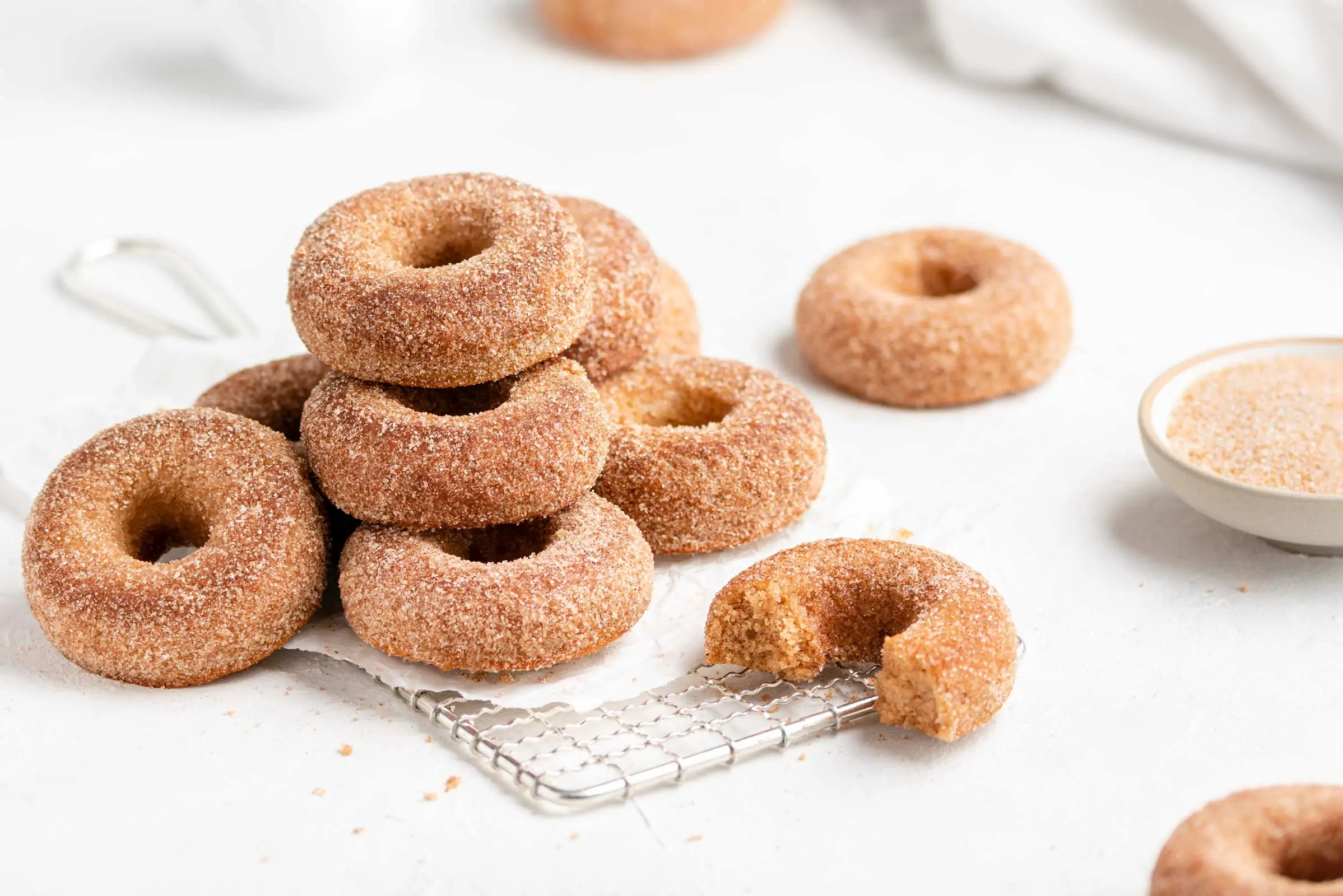 Apfel-Donuts aus dem Backofen mit einem Topping aus Zimt und Zucker auf einem Abkühlgitter gestapelt.
