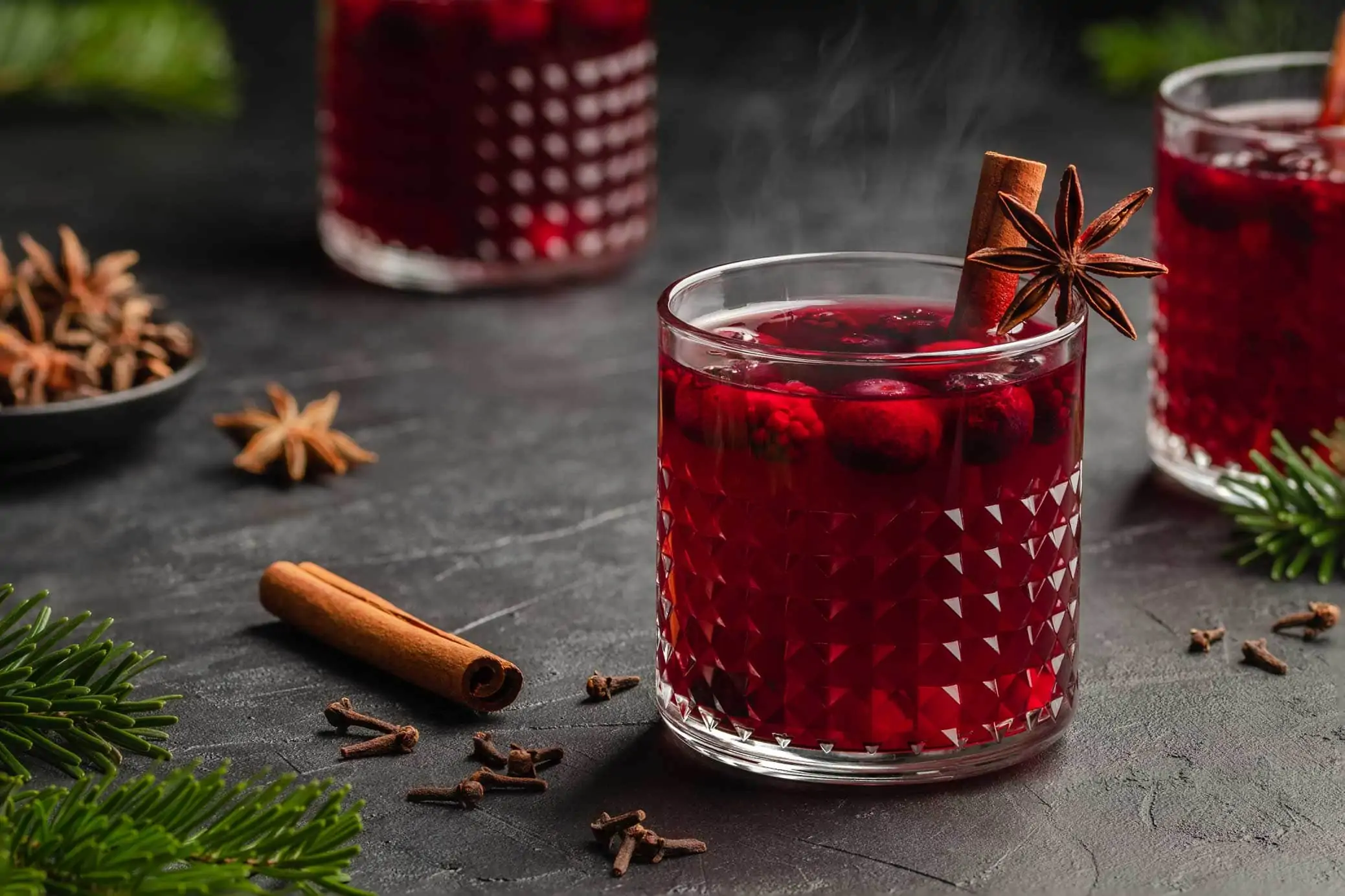 Lillet Hot Berry mit Beeren und einer Zimtstange darin. Der rote Punsch ist so heiß, dass er noch dampft.