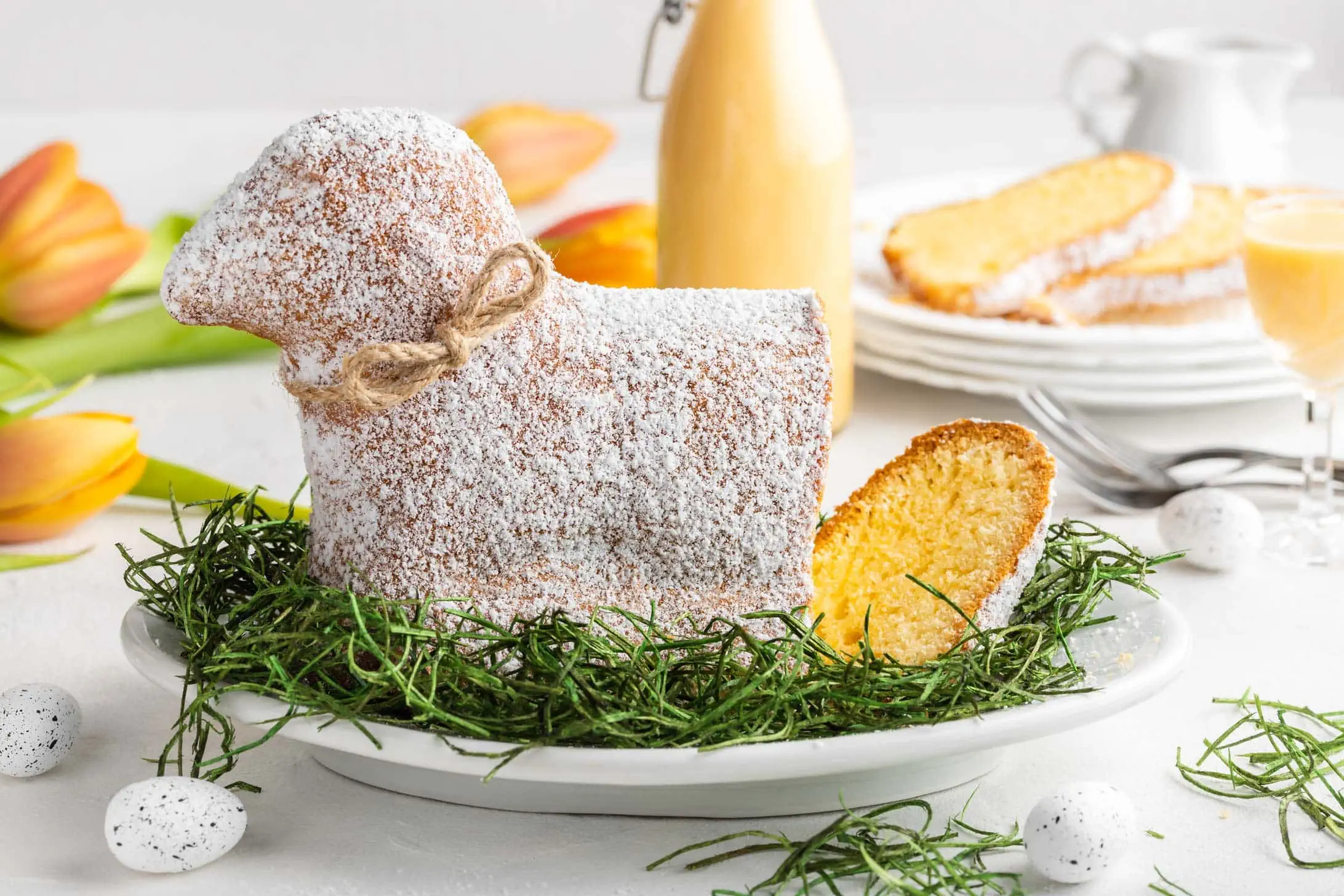 Ein aufgeschnittenes Osterlamm mit Eierlikör liegt auf einem Teller. Im Hintergrund liegen kleine Ostereier.