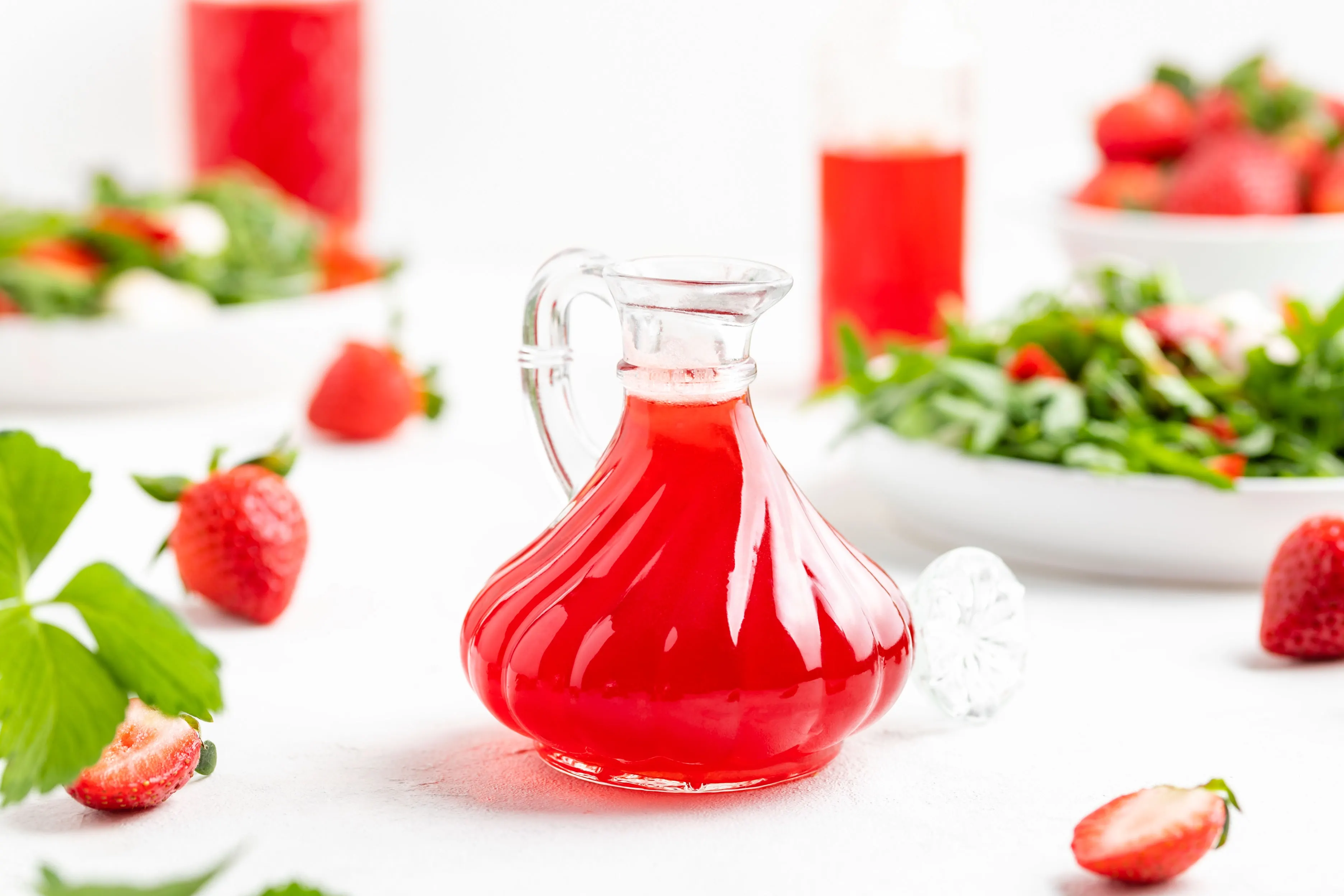 Selbstgemacher Erdbeeressig in einer kleinen Flasche. Im Hintergrund liegen frische Erdbeeren.