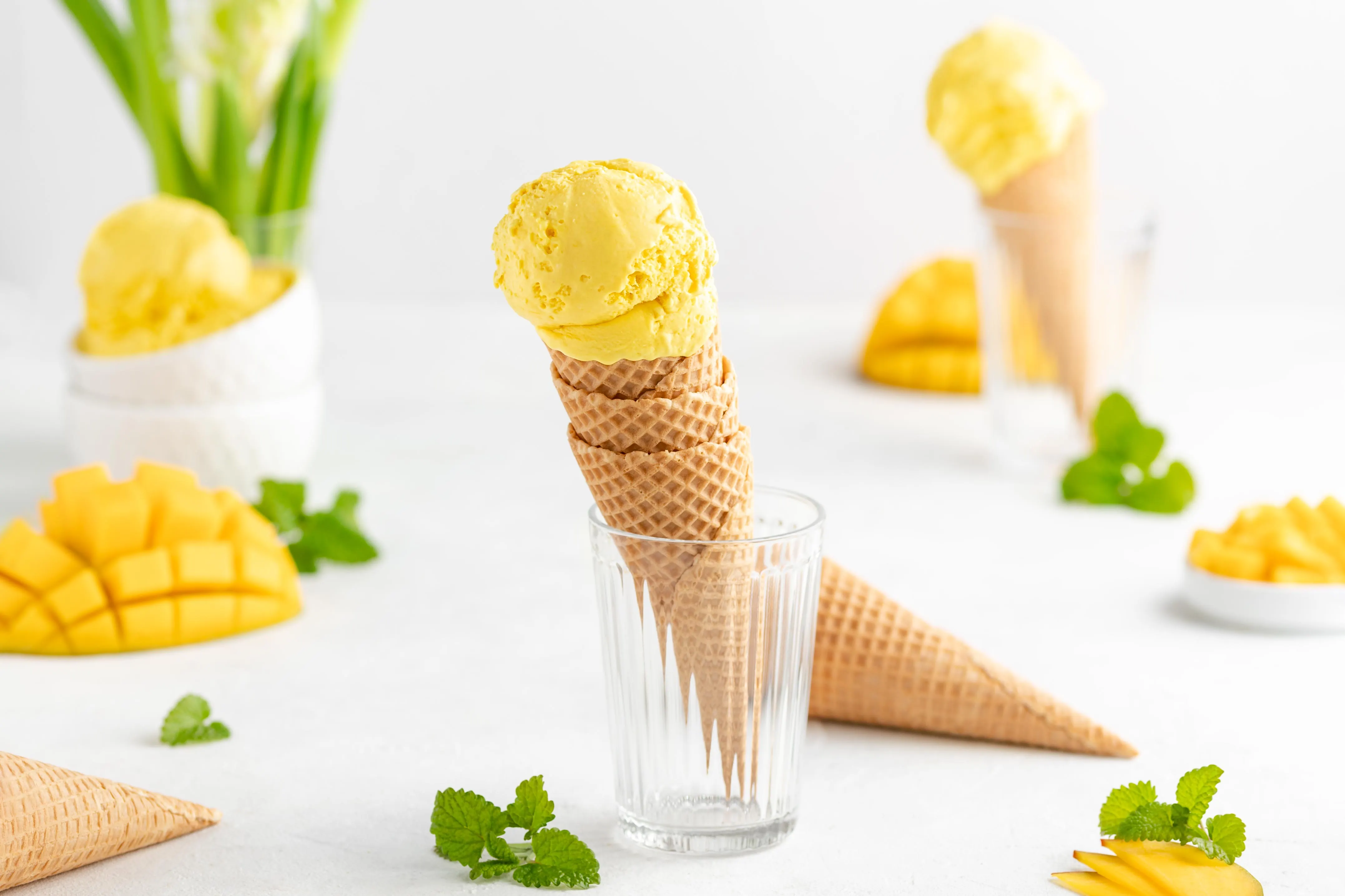 Eine Kugel cremiges Mangoeis aus der Eismaschine in einer Eiswaffel.