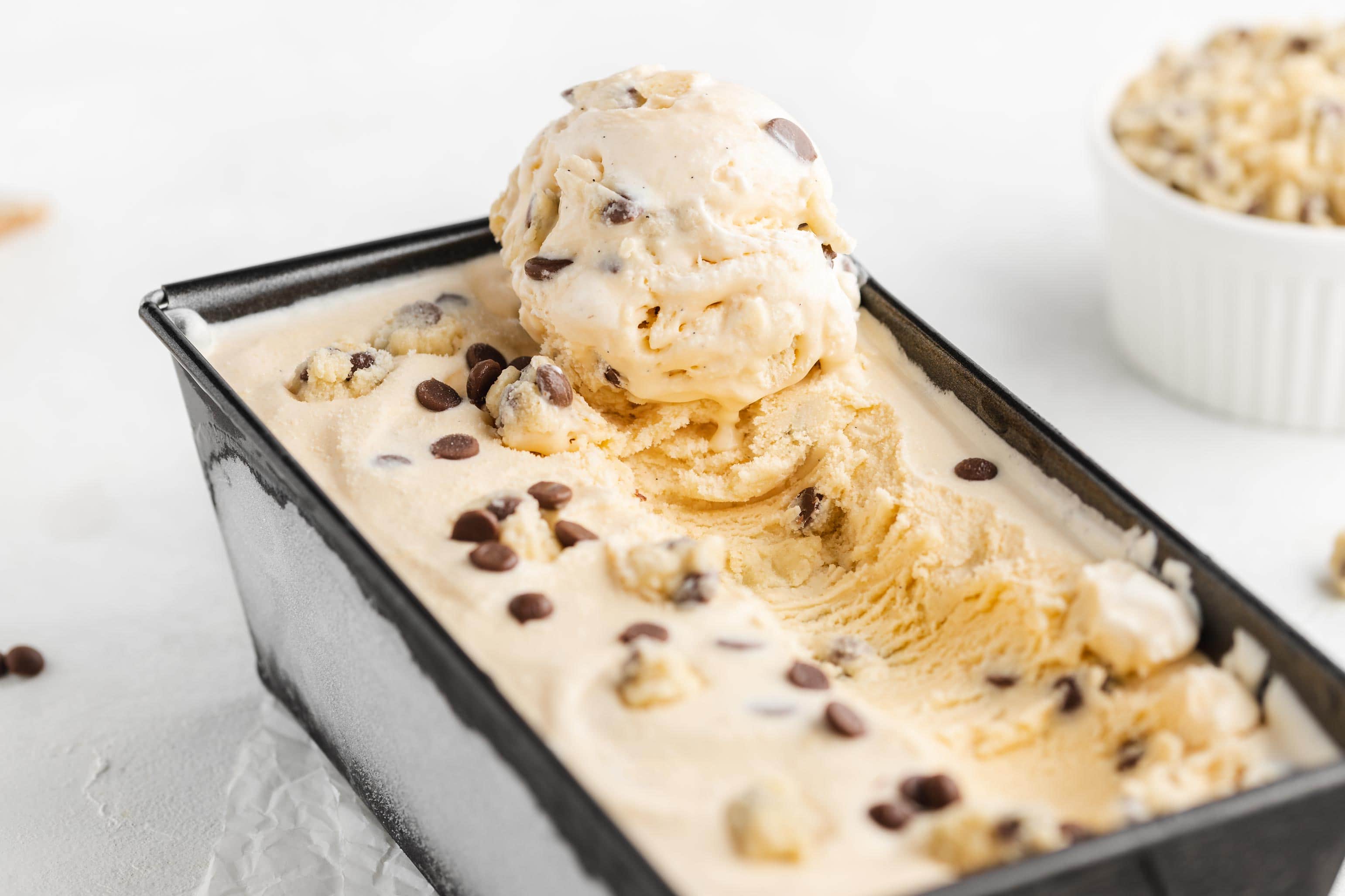 Cremiges Cookie Dough Eis in einer Form abgefüllt. Auf dem Eis liegt eine geformte Eiskugel.