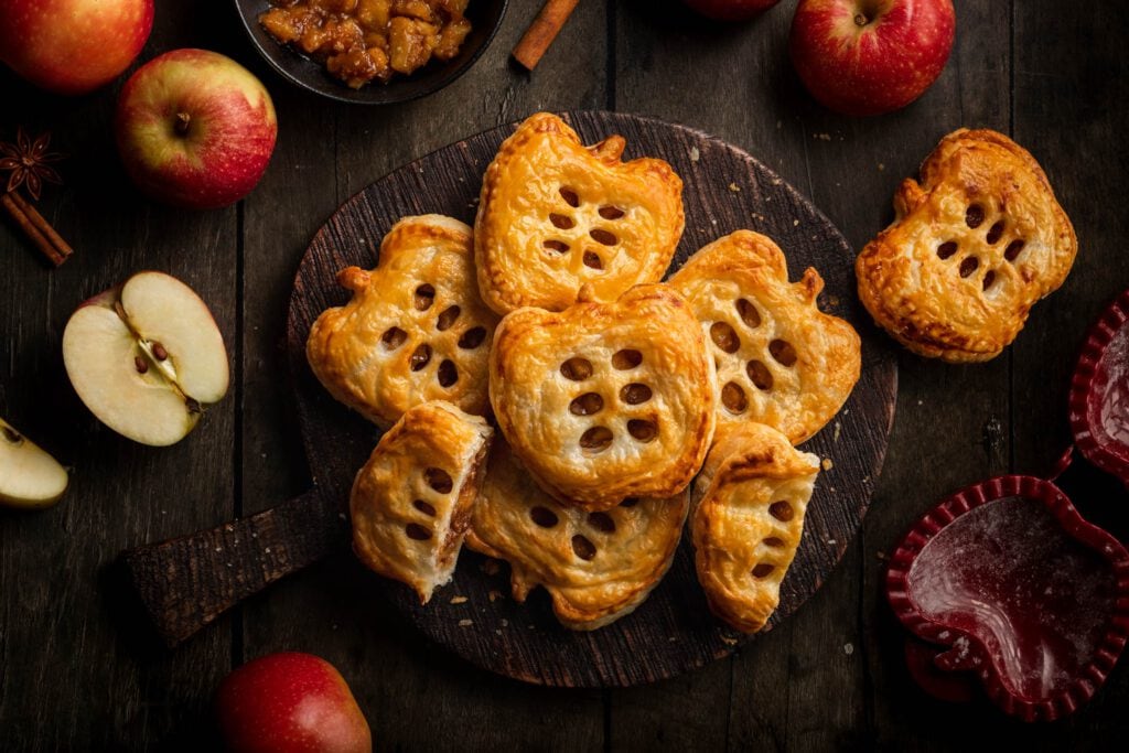 Schnelle Apfeltaschen mit Blätterteigin Form von Äpfeln serviert auf einem Holzbrett.