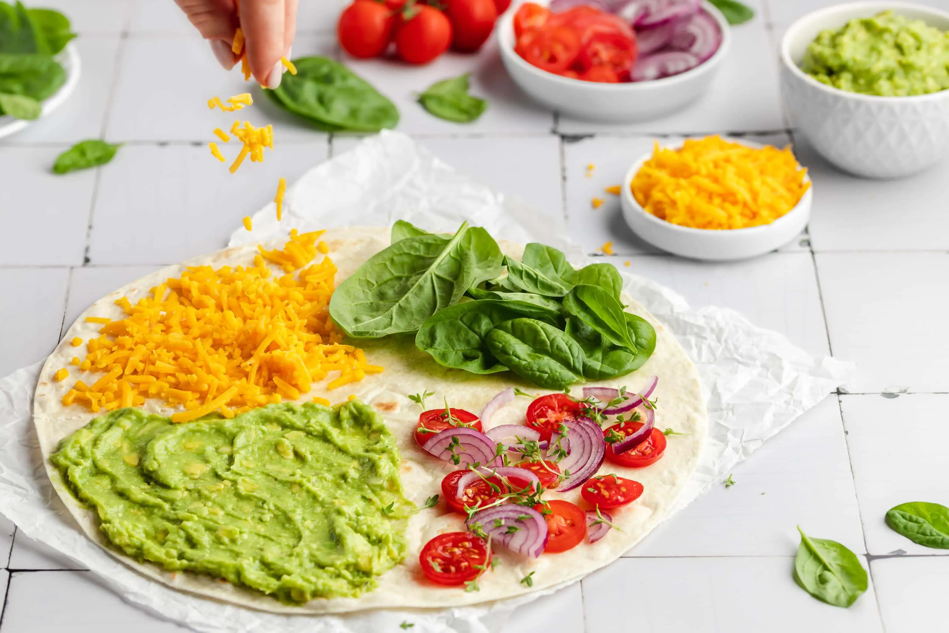 Ein Wrap mit Guacamole, Spinat, Tomaten, Zwiebeln und Käse, der nach dem TikTok-Trend gefaltet wird.