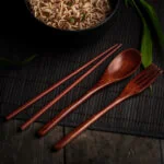 Asiatisches Besteck aus Holz vor einer Schüssel mit japanischen Nudeln.