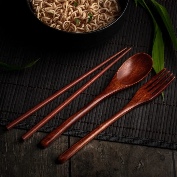 Asiatisches Besteck aus Holz vor einer Schüssel mit japanischen Nudeln.