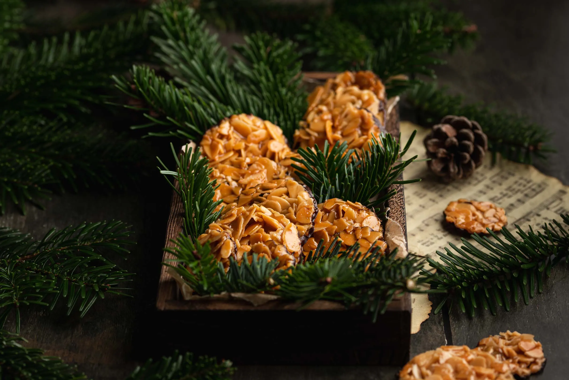 Schnelle Florentiner Plätzchen aus karamellisierten Mandelblättchen mit dunkler Schokolade auf einem Holztablett.