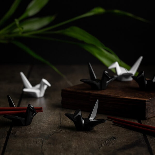 Schwarze und weiße Origami-Kraniche, die als Ablage für Essstäbchen dienen.