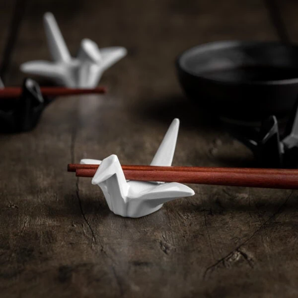 Mehrere Essstäbchen Ablagen in Form von Origami-Kranichen auf einem hölzernen Untergrund.