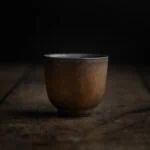 Eine kleine Teetasse aus Keramik in der Farbe gold-schwarz im japanischen Stil.