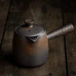 Eine Kyusu Teekanne mit Seitengriff in der Farbe gold-schwarz mit einem passendem Deckel.