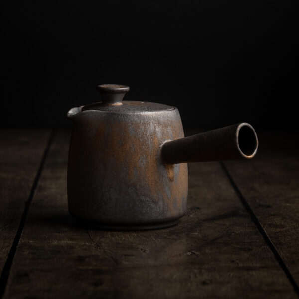 Eine Kyusu ist eine traditionelle japanische Teekanne mit Seitengriff auf einem dunklen Untergrund.