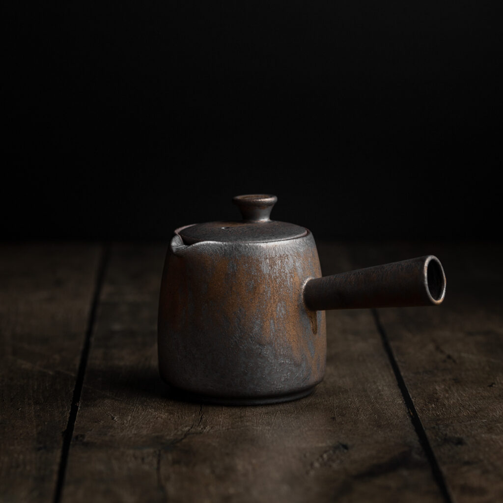 Traditionelle japanische Teekanne Kyusu mit Seitengriff auf einem dunklen Untergrund.