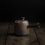 Traditionelle japanische Teekanne Kyusu mit Seitengriff auf einem dunklen Untergrund.