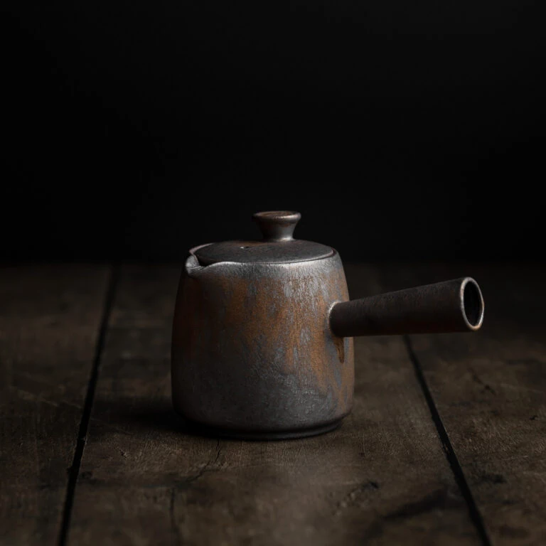 Traditionelle japanische Teekanne Kyusu mit Seitengriff auf einem dunklen Untergrund.
