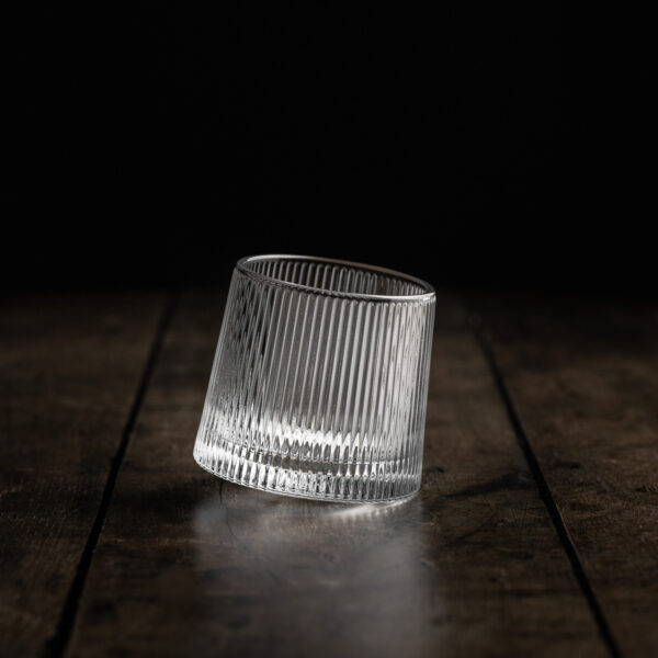 Ein ausgefallenes Whiskyglas mit rundem Boden auf einem Holztisch.