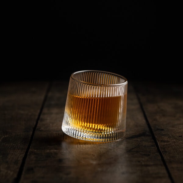 Ein rotierendes Wackelglas gefüllt mit Whisky steht auf einem Tisch.