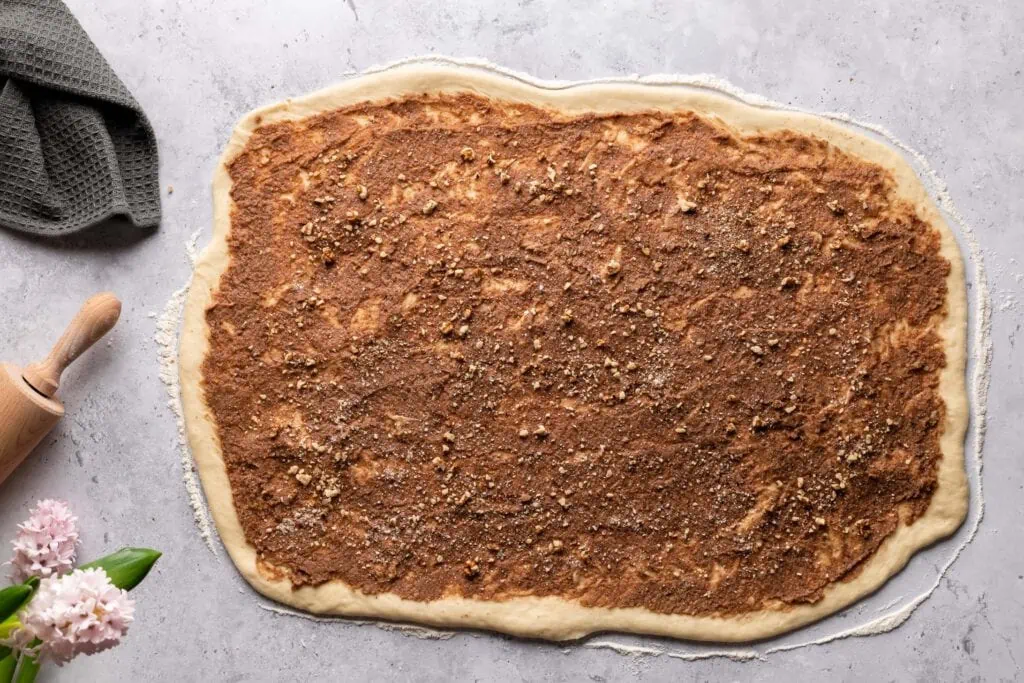 Der ausgerollte Teig für den Hefekranz bestrichen mit der Marzipan-Nuss-Füllung.