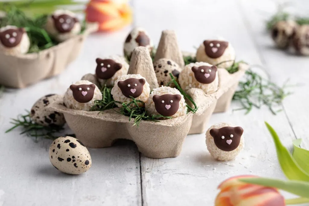 Süße Osterpralinen in der Form von kleinen Schäfchen in einem Osternest.