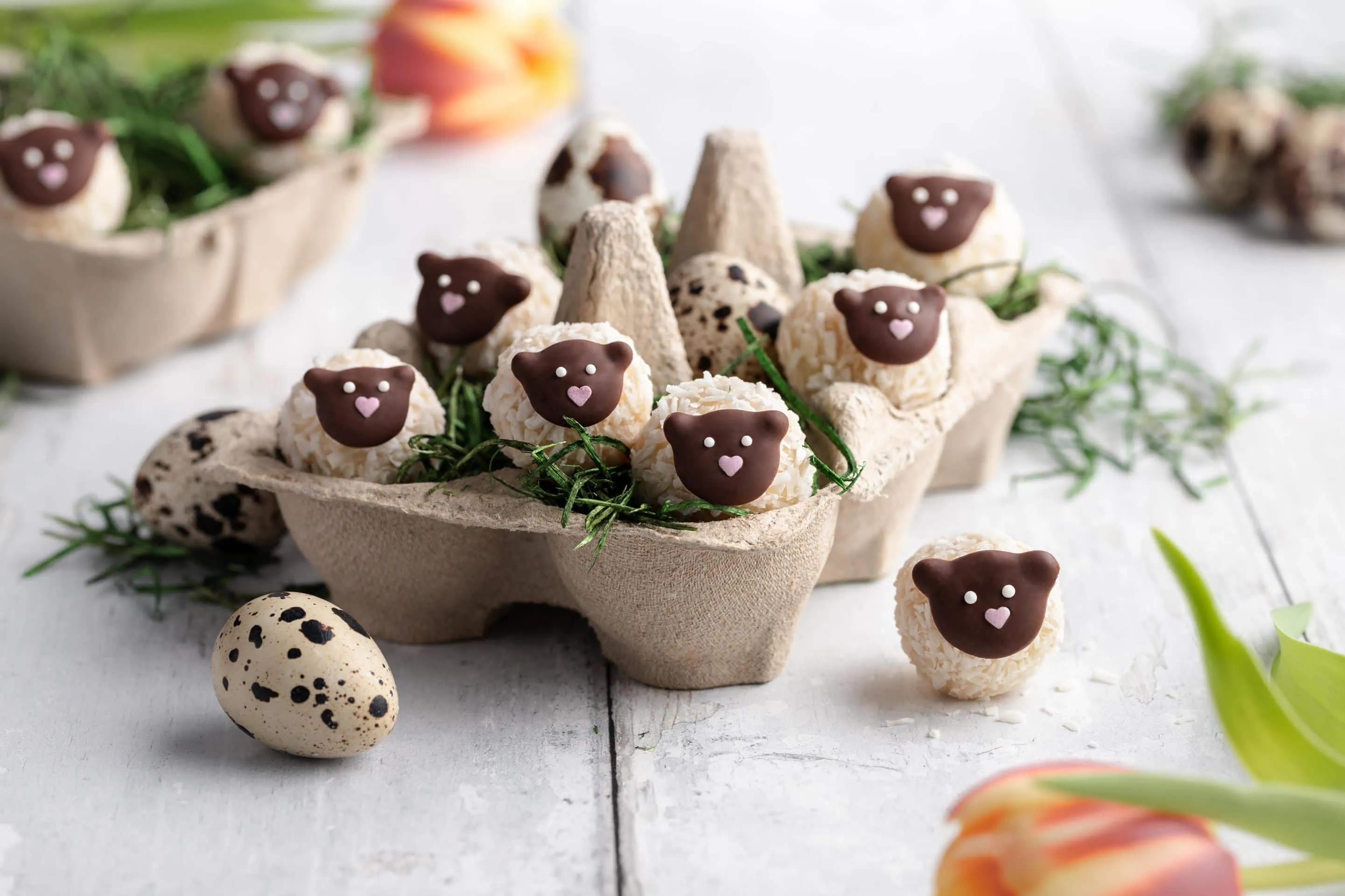Süße Osterpralinen in der Form von kleinen Schäfchen in einem Osternest.