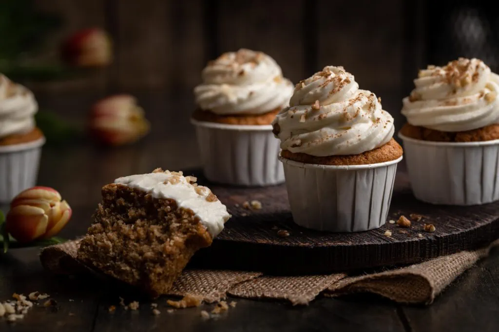 Saftige Karotten Cupcakes mit Frischkäse-Frosting in weißen Papierförmchen.
