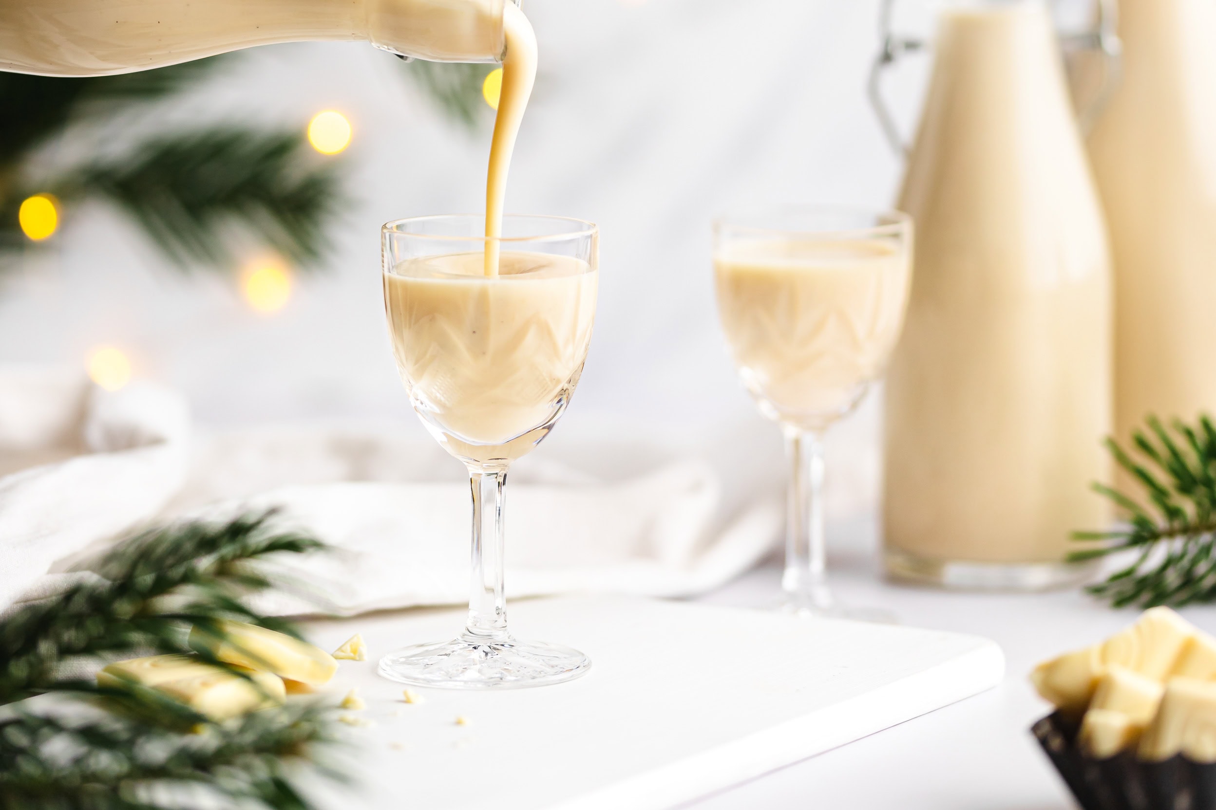 In ein schönes Likörglas wird gerade der weiße, cremige Marzipanlikör eingeschenkt.