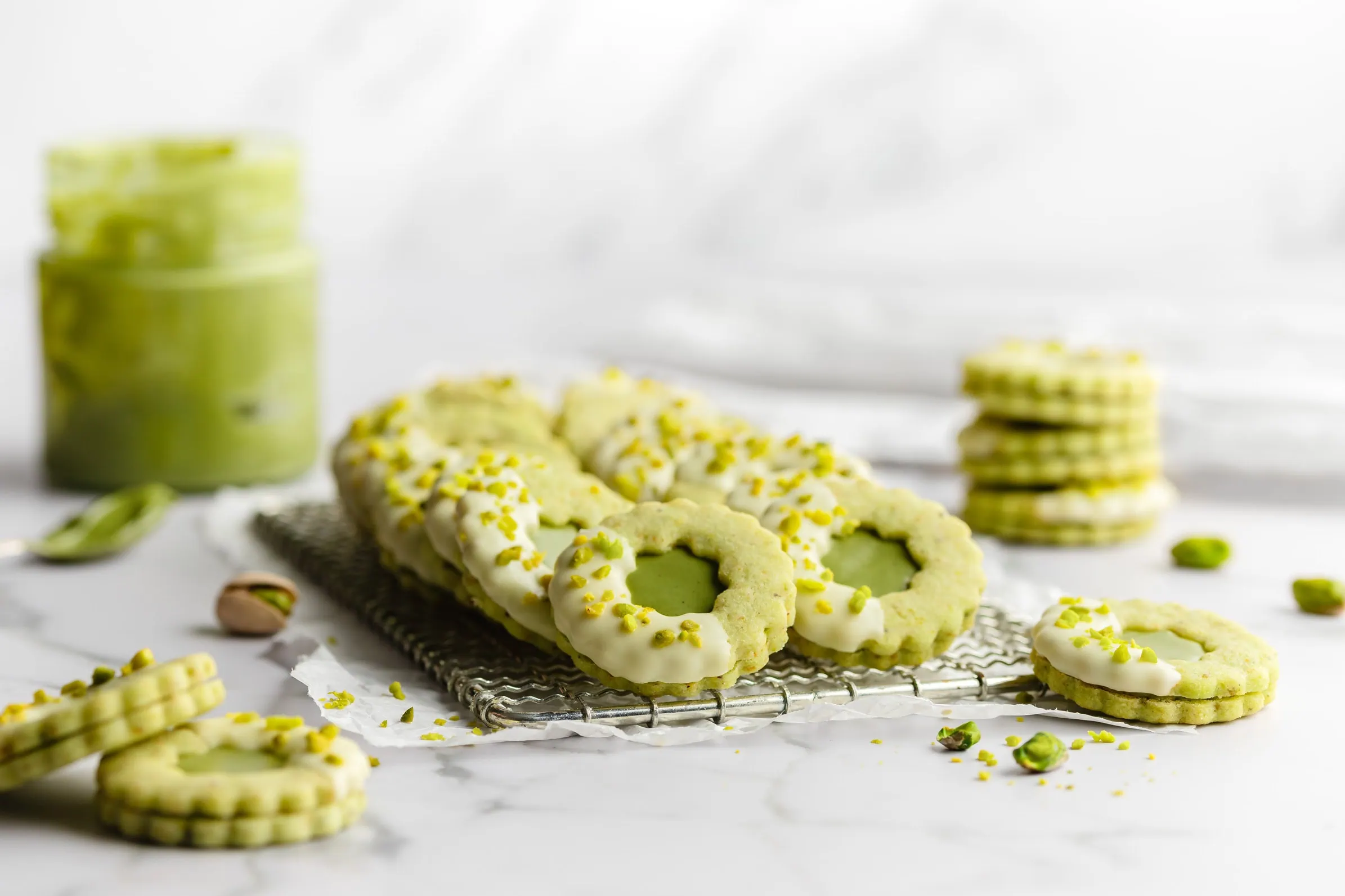 Feine Pistazien-Plätzchen mit Cremefüllung auf einem Kuchengitter.