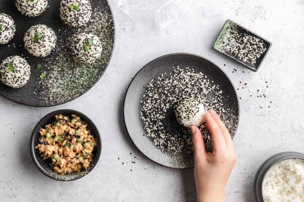 Die Zubereitung der Sushi Balls wird durch das Wälzen der Reis-Bällchen in Sesam abgeschlossen.