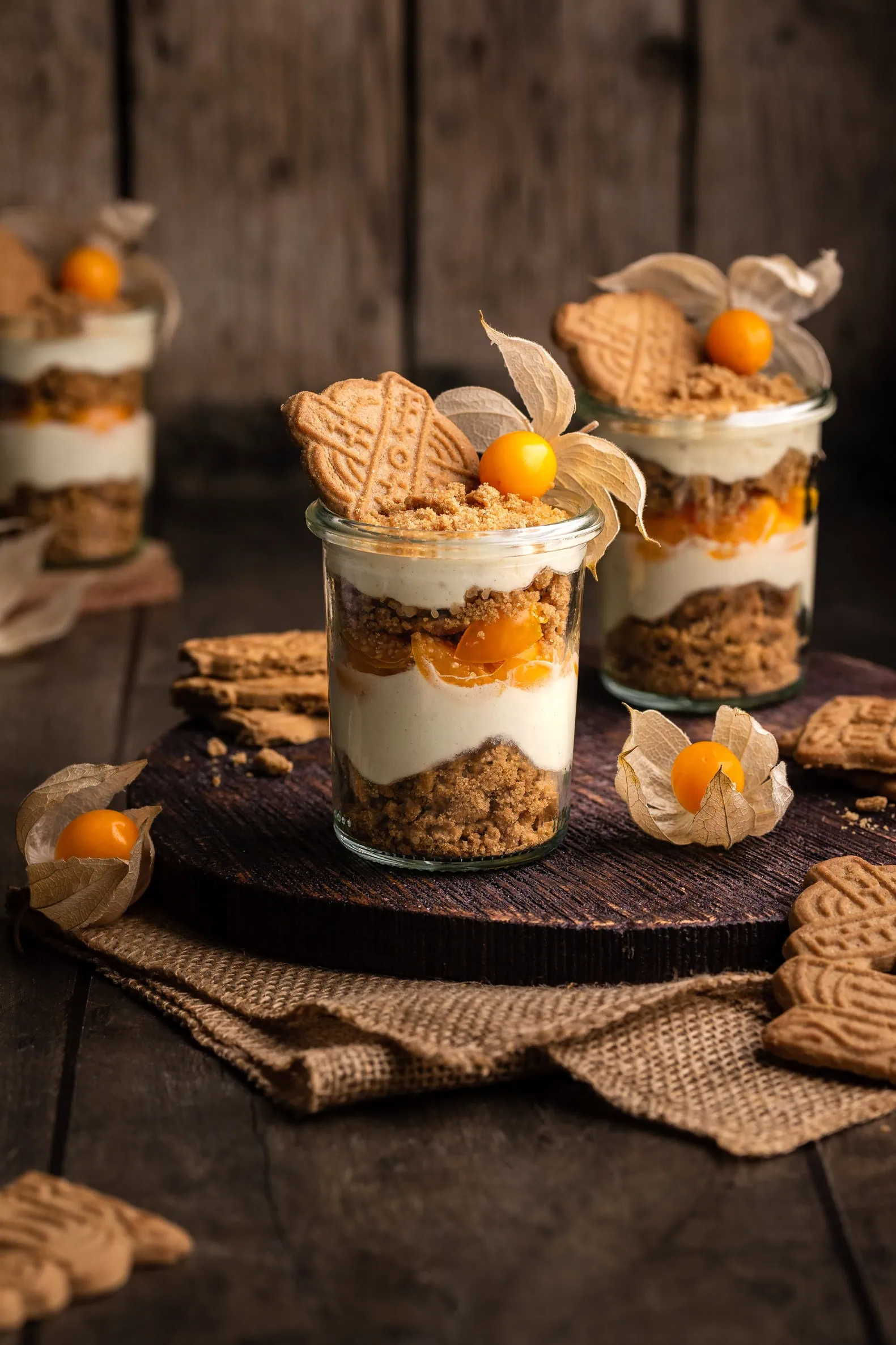 Mehrere Gläse von einem Spekulatius Dessert mit Mascarpone und Physalis fürWeihnachten.