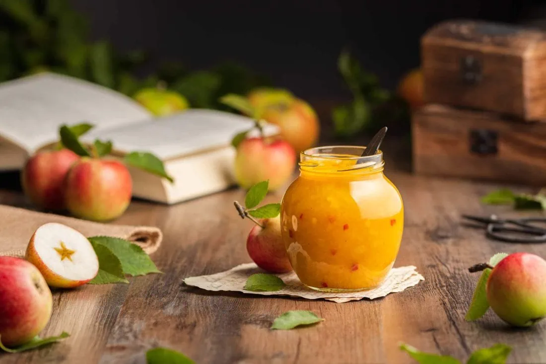 Ein herbstlich gedeckter Tisch mit einem süß-pikanten Apfel Chutney darauf. In dem Chutney sind kleine Chilistücke.