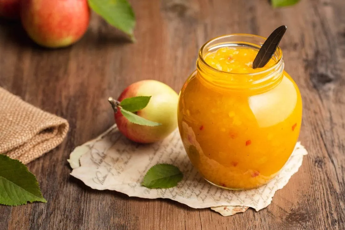 Süß-pikantes Apfel Chutney mit Chili in einem Schraubglas mit einem Löffel darin.