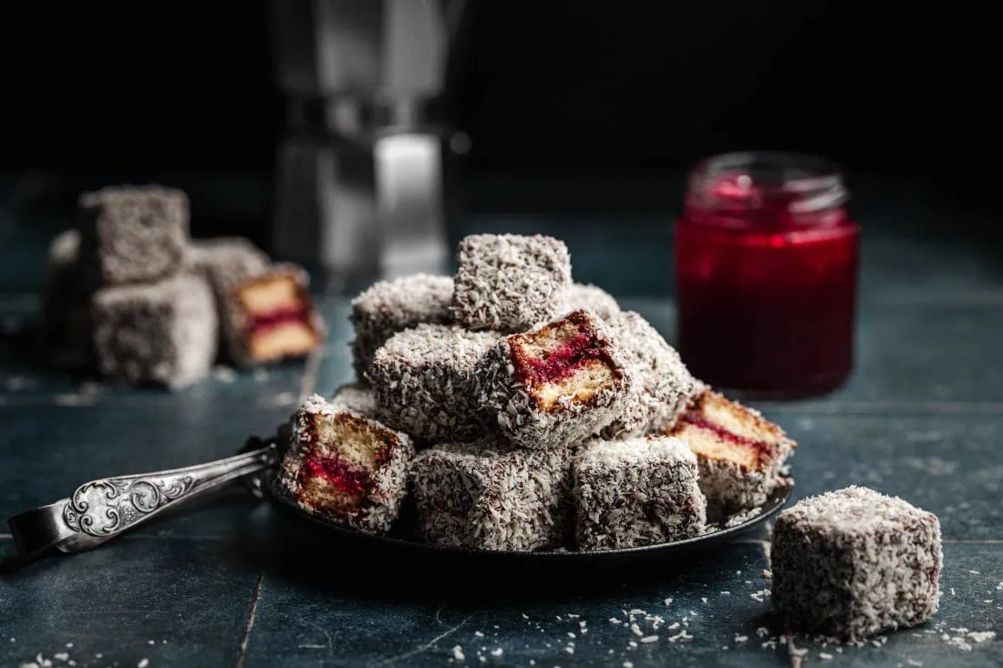 Australische Lamingtons, auch Cupavci genannt, liegen übereinander auf einem Teller.