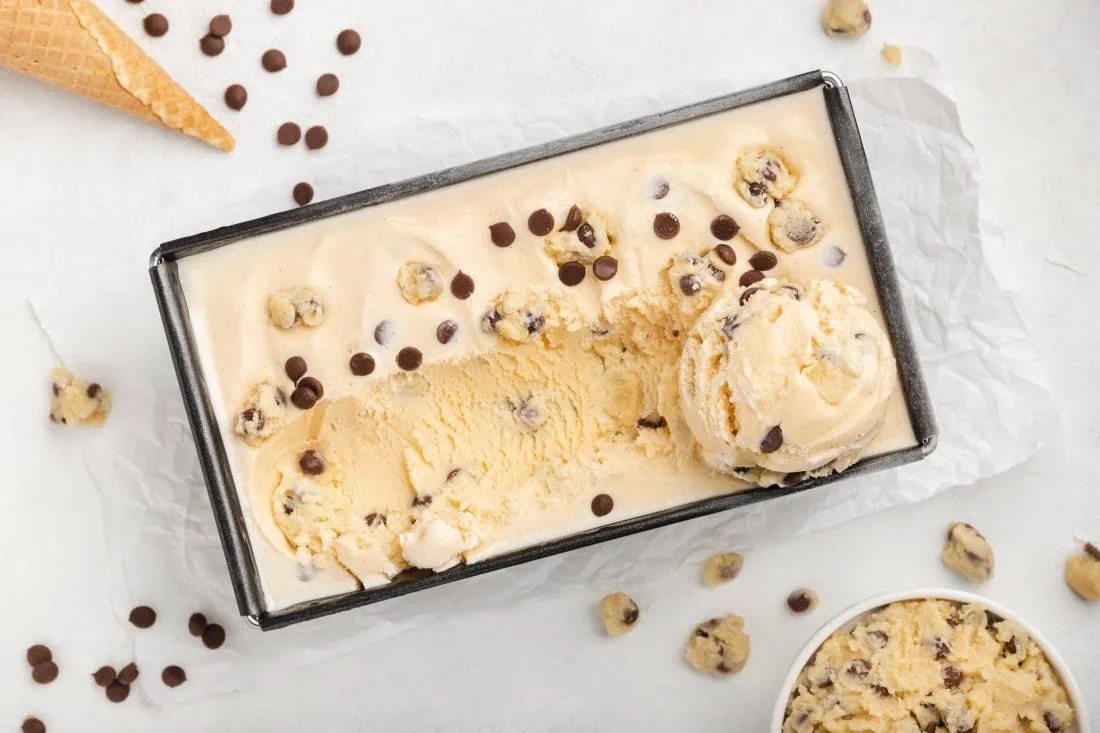 Cookie Dough Eis aus der Eismaschine in einer Form. Daneben steht ein Schälchen mit Cookie Dough.