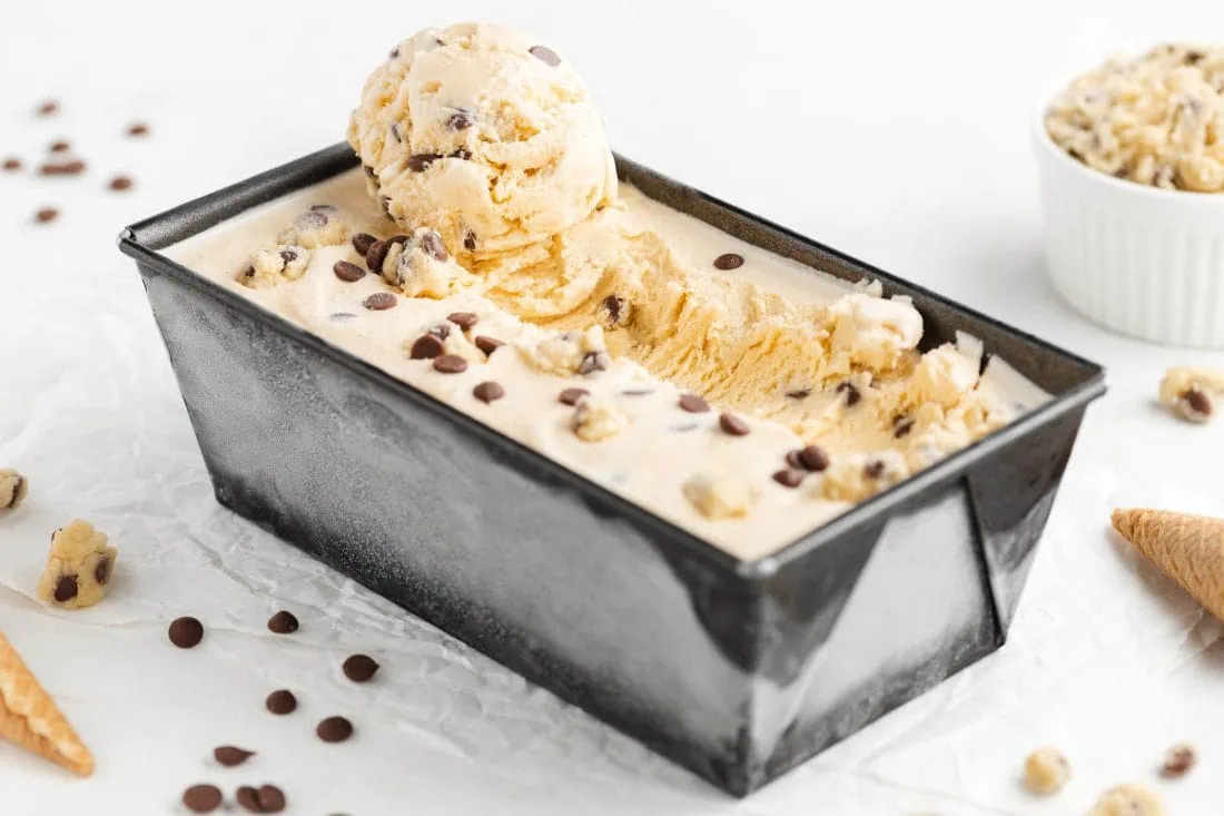 Cookie Dough Eis in einer Form. Auf dem Eis liegen Teigstücke und Chocolate Chips.