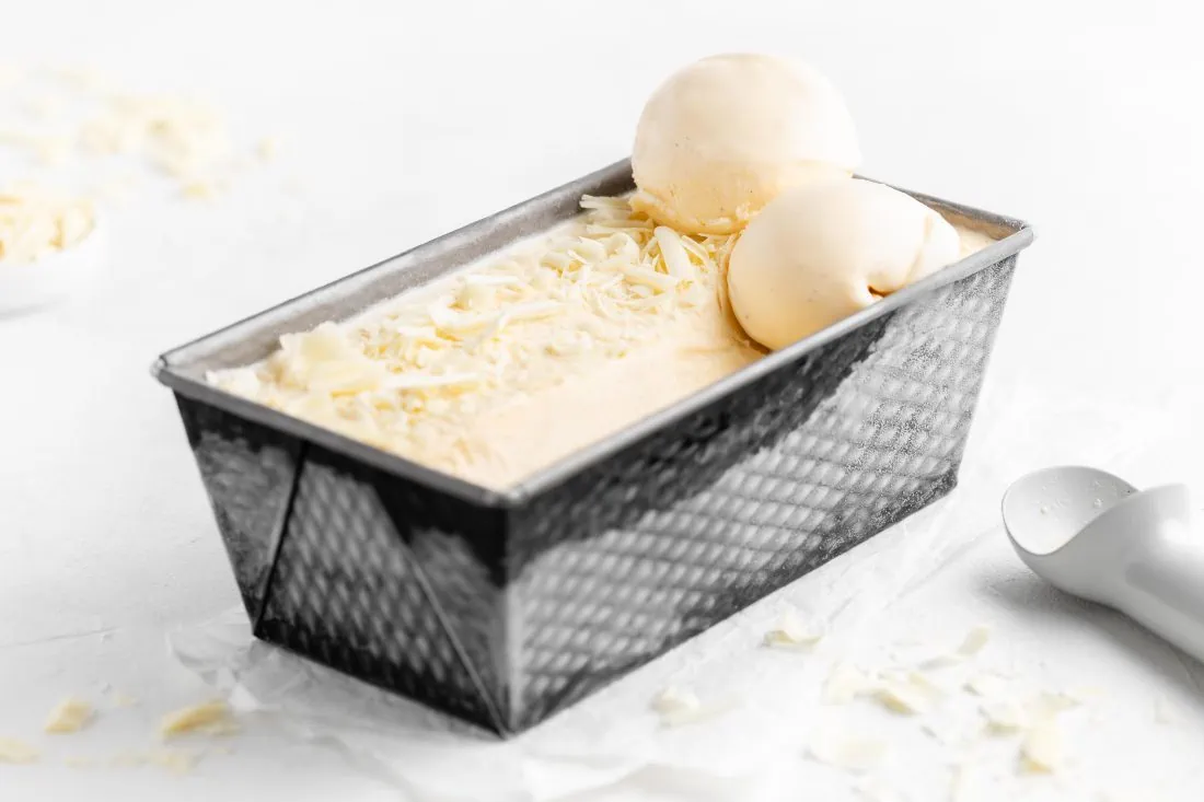 Super cremiges, weißes Schokoladeneis aus der Eismaschine abgefüllt in eine Form zum Einfrieren.
