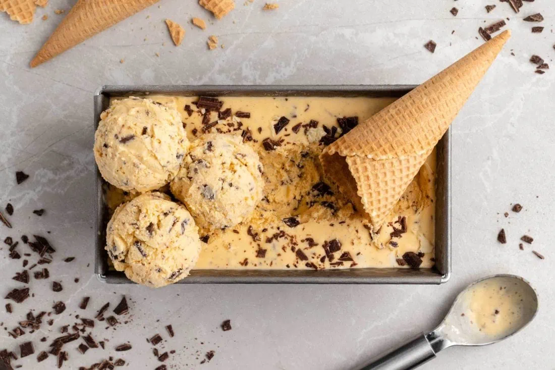 Eierlikör-Eis in einer Kastenform mit einer Eiswaffel und mehreren Eiskugeln darauf.
