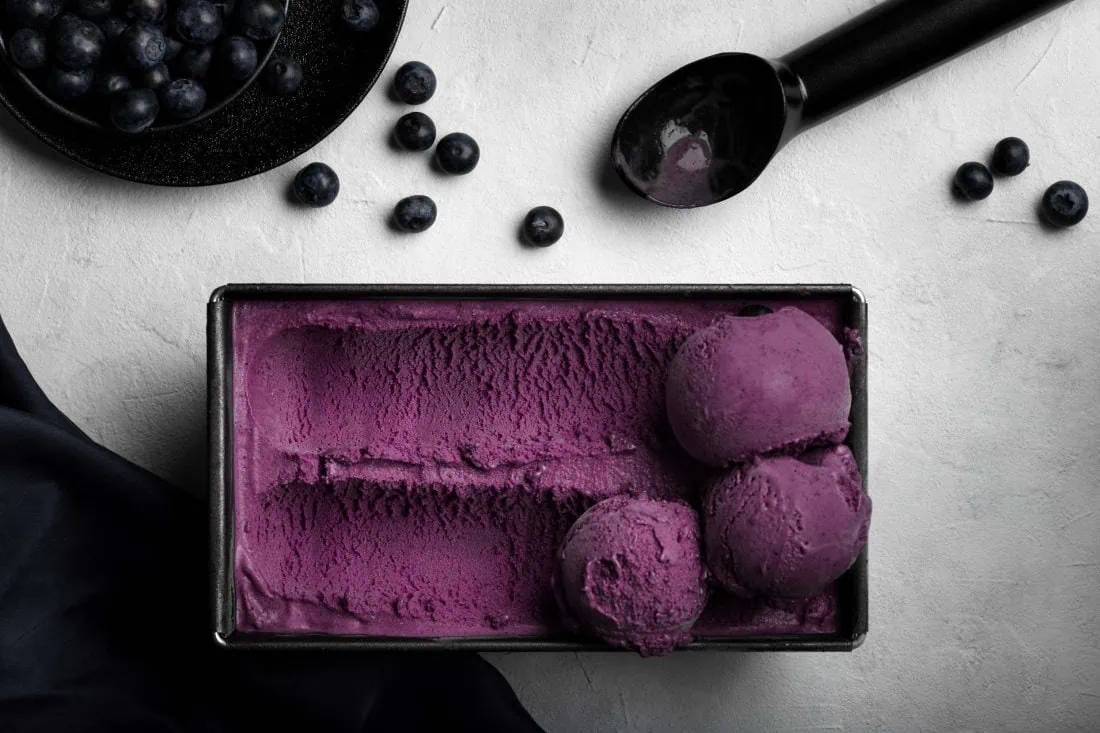 Fruchtiges Blaubeereis aus der Eismaschine in einer intensiven lilalen Farbe in einer Form.
