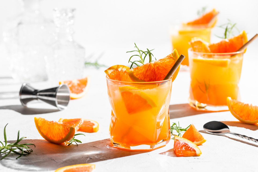 Gin Spritz Cocktail, ein Aperitif aus Gin, Prosecco, Orangensaft und Aperol serviert in schicken Gläsern.