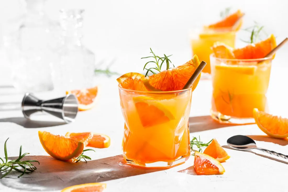 Gin Spritz Cocktail, ein Aperitif aus Gin, Prosecco, Orangensaft und Aperol serviert in schicken Gläsern.