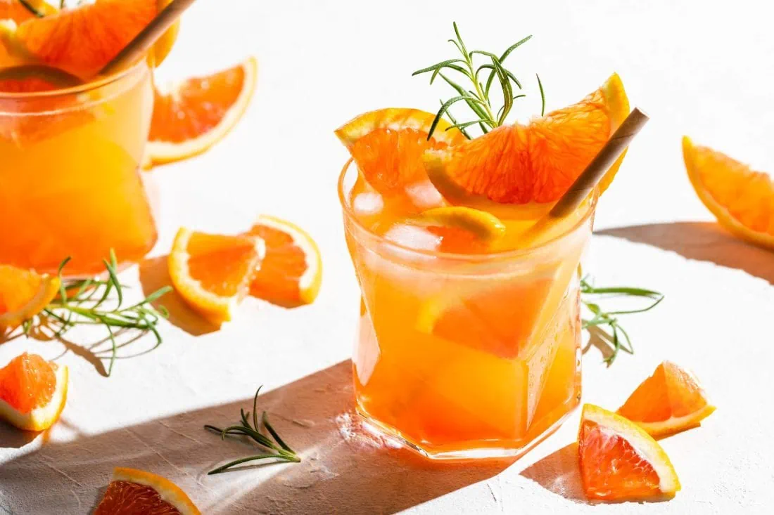 Gin Spritz mit Eiswürfeln serviert in einem Tumbler mit einem Strohhalm.