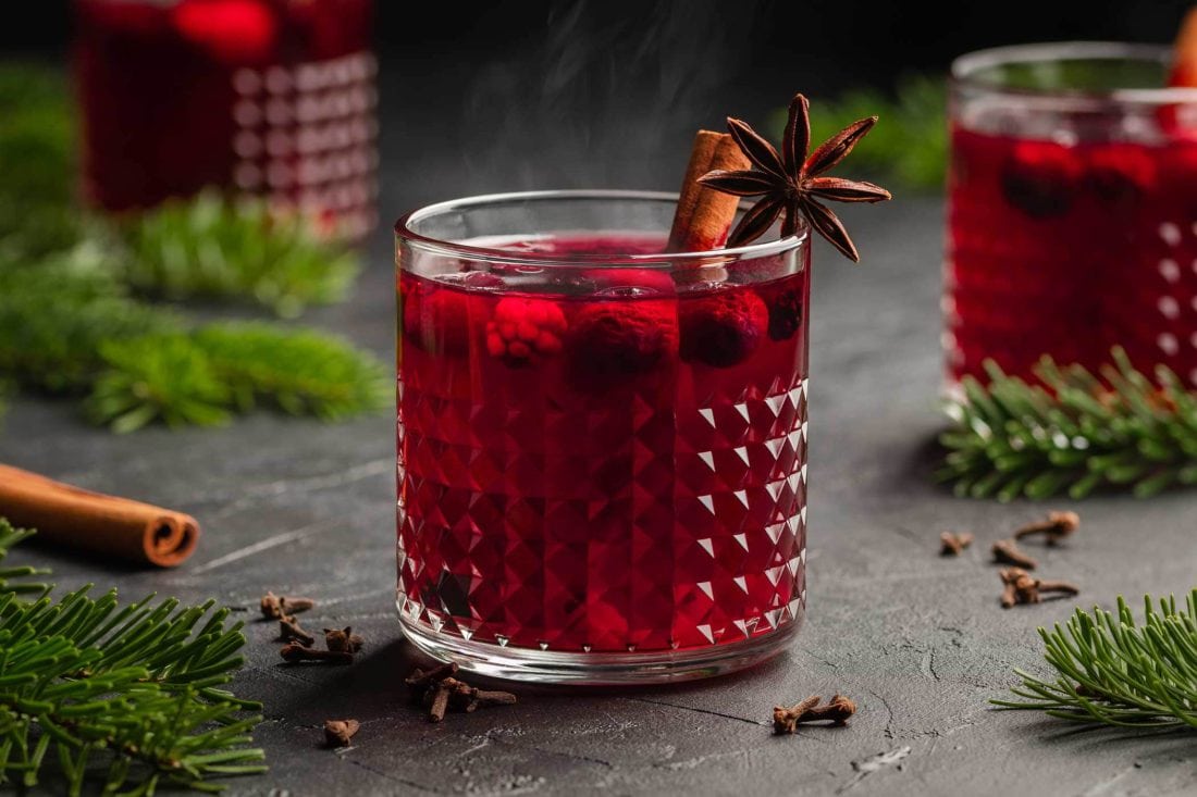 Lillet Hot Berry mit Beeren in einem Glas. Das Glas ist garniert mit Sternanis und einer Zimtstange.