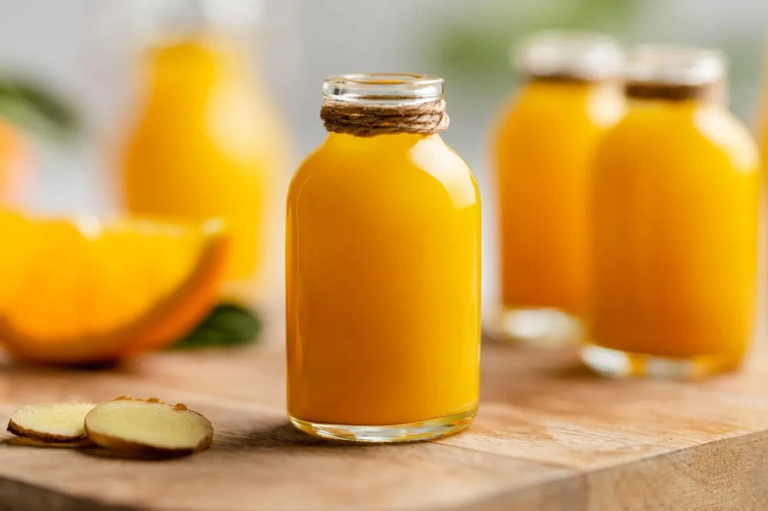 Mehrere Ingwer Shots mit Orange in kleinen Glasflaschen abgefüllt.