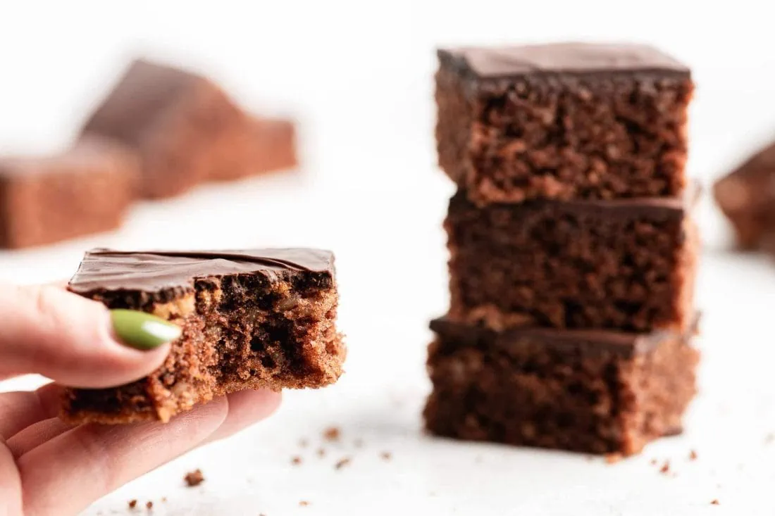 Naheaufnahme einer Hand, die ein Stück Lebkuchen hält. Ein Stück von der Lebkuchen-Schnitte ist bereits abgebissen.
