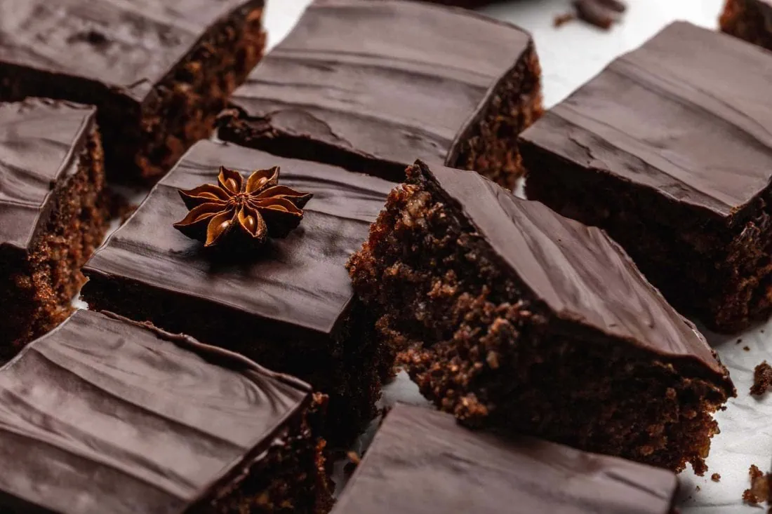 Schneller Lebkuchen von Blech mit einem Guss aus Zartbitterschokolade und mit Nüssen im Teig zu Schnitten portioniert.